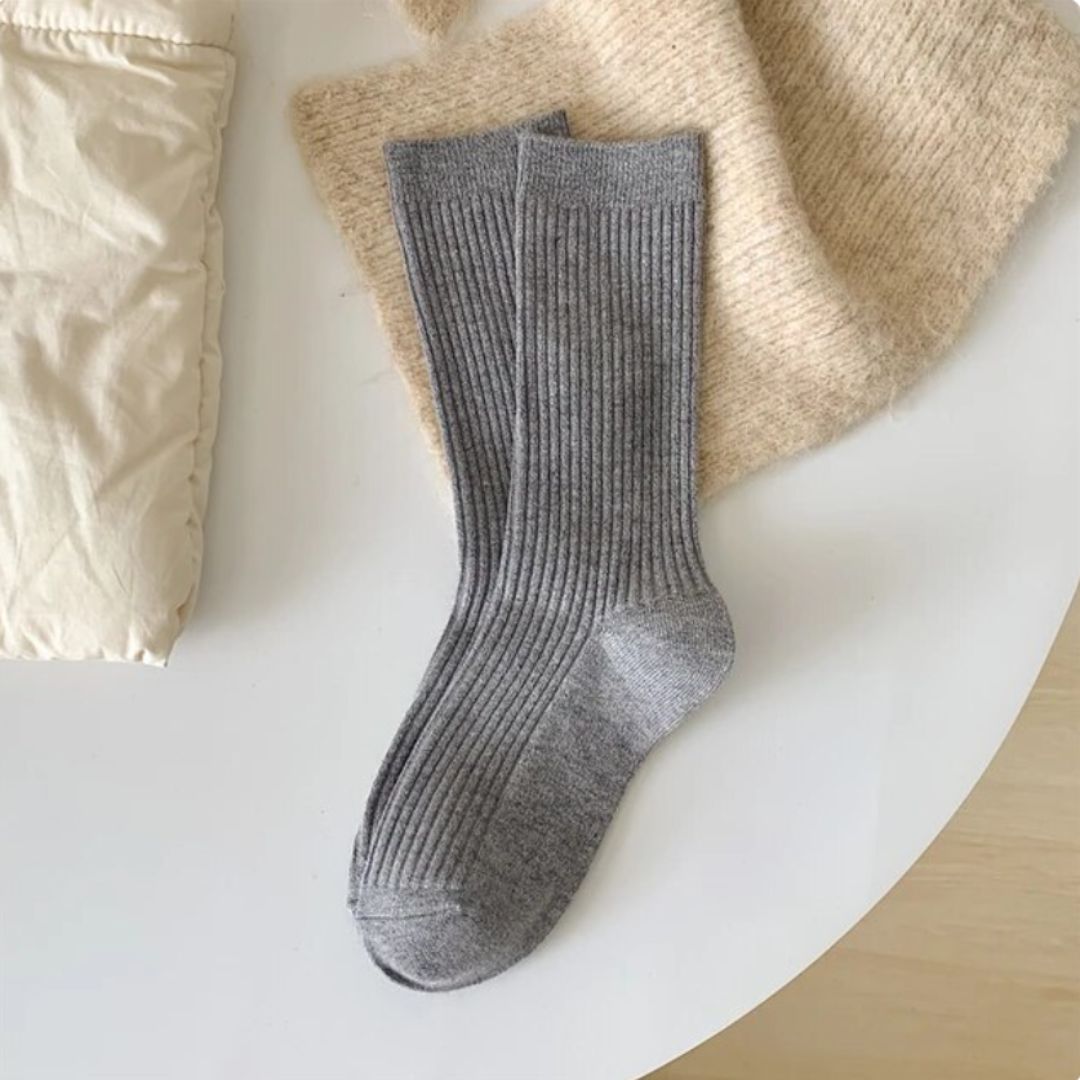 Graue gerippte Wollsocken auf beigem Strickstoff, gemütliche Wintermode Accessoire.