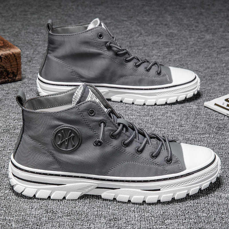 Graue High-Top-Sneaker aus Leder mit weißer Sohle auf grauem Teppich.