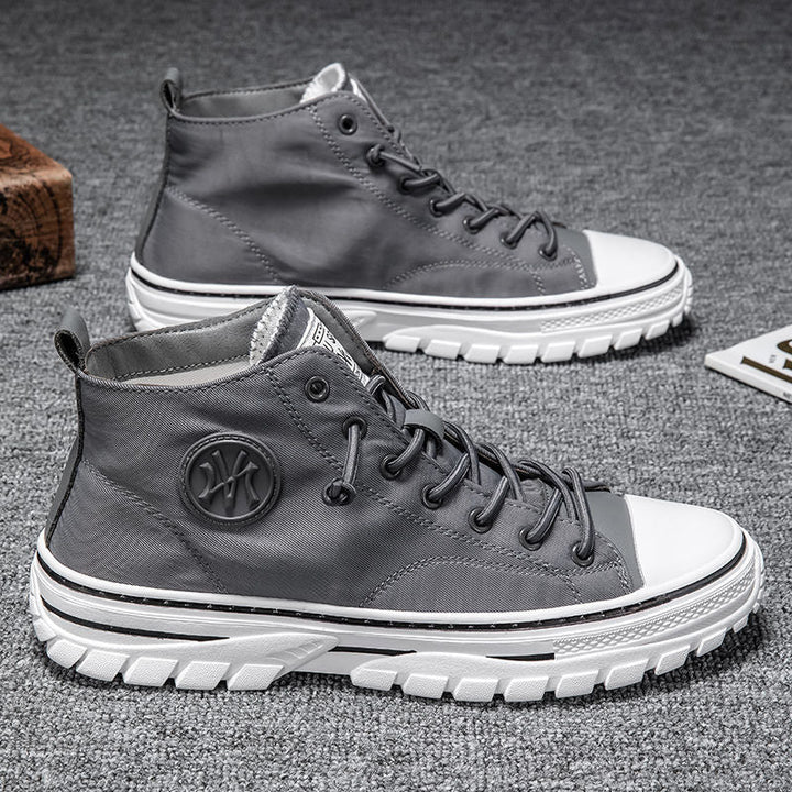 Graue High-Top-Sneaker aus Leder mit weißer Sohle auf grauem Teppich.
