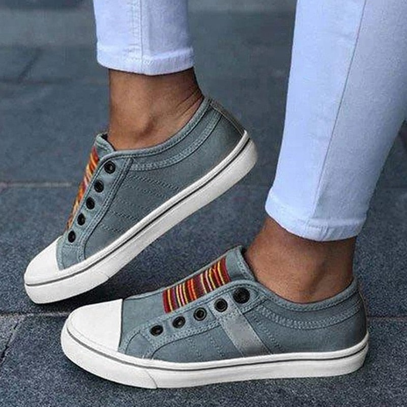 Graue Sneaker ohne Schnürsenkel, bunte Streifen, Damenmode, Freizeitschuhe, Straßenstil.