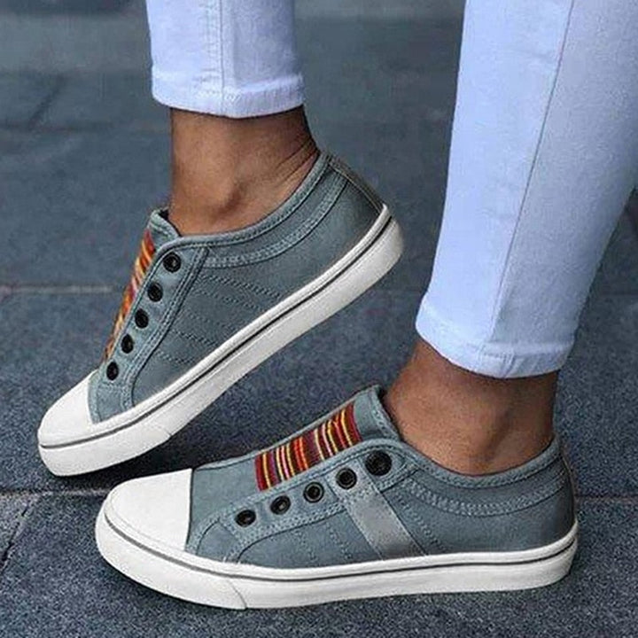 Graue Sneaker ohne Schnürsenkel, bunte Streifen, Damenmode, Freizeitschuhe, Straßenstil.