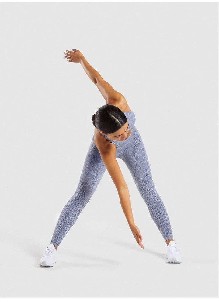 Frau in grauer, nahtloser Sportleggings beim Dehnen, Fitnessbekleidung, bequem, elastisch.