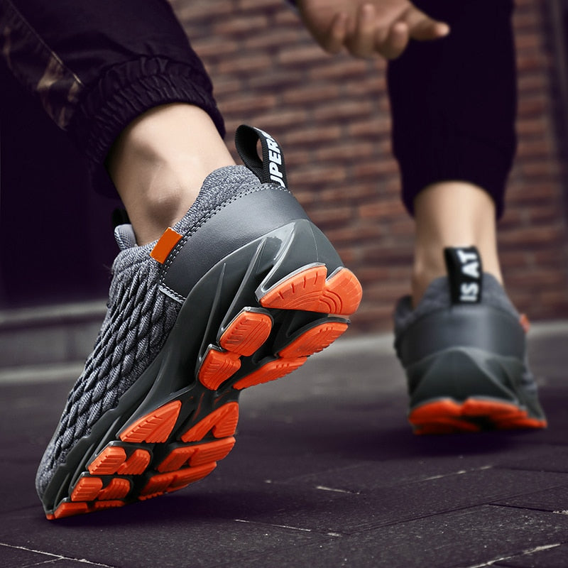 Graue Sportschuhe mit oranger Sohle, atmungsaktiv, rutschfest, ideal für Laufen und Fitness.