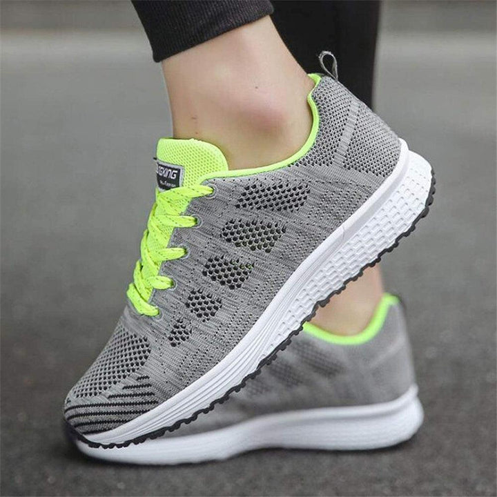 Graue Damen-Laufschuhe mit neon-gelben Akzenten, atmungsaktives Mesh, rutschfeste Sohle.