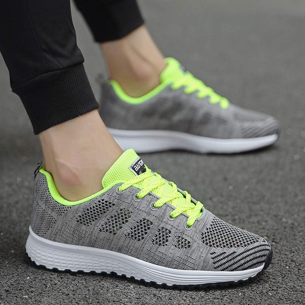 Graue Sportschuhe mit neon-gelben Schnürsenkeln, atmungsaktiv, ideal zum Laufen.