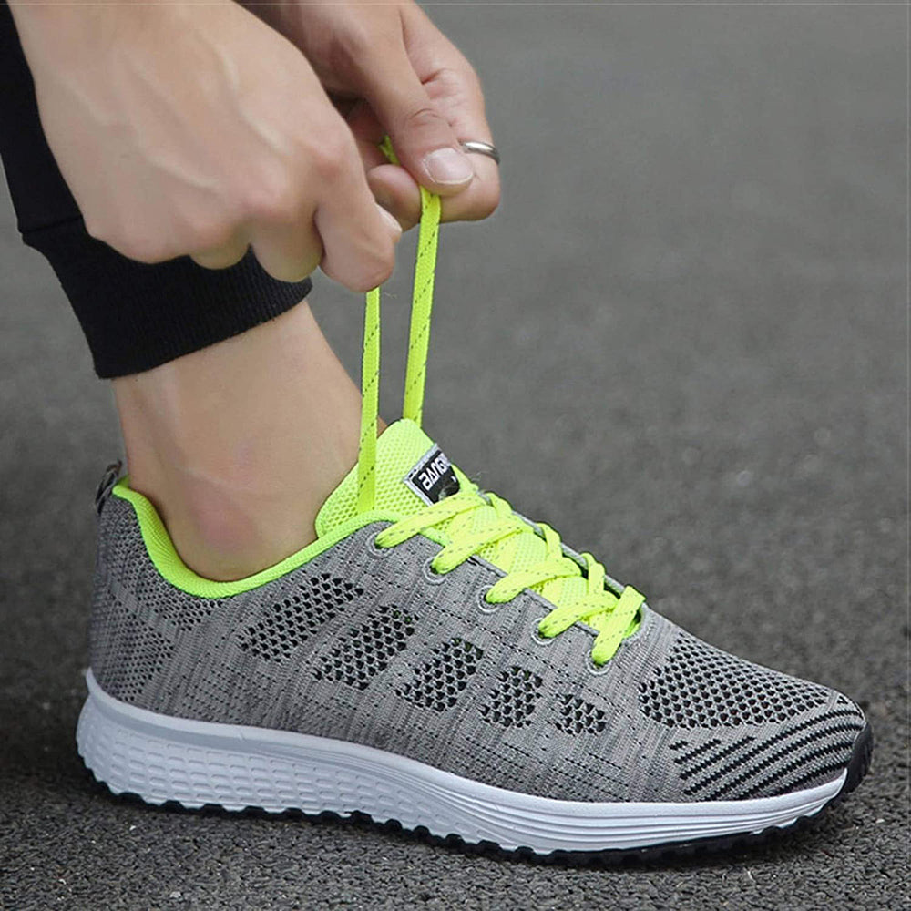 Grauer Sportschuh mit neongelben Schnürsenkeln, atmungsaktiv, ideal für Laufen und Fitness.