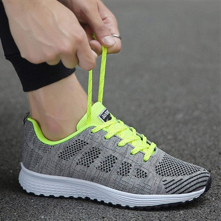 Grauer Sportschuh mit neongelben Schnürsenkeln, atmungsaktiv, ideal zum Laufen.