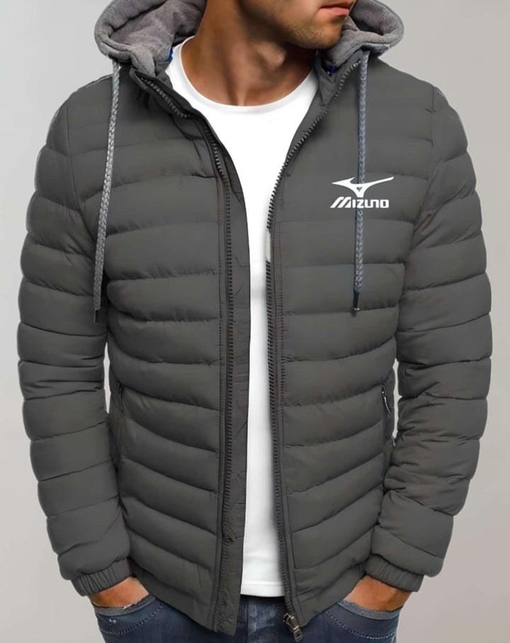 Mann in grauer Mizuno-Daunenjacke mit Kapuze, weißem T-Shirt und blauer Jeans.