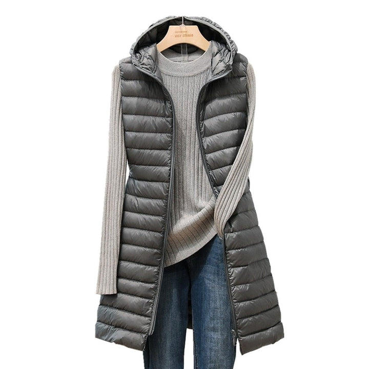 Graue gesteppte Damenweste mit Kapuze, über grauem Pullover und blauer Jeans auf Kleiderbügel.