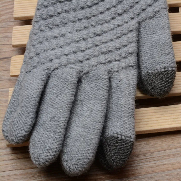 Grauer gestrickter Handschuh aus Wolle auf Holzuntergrund, winterfest, warm, modisch.