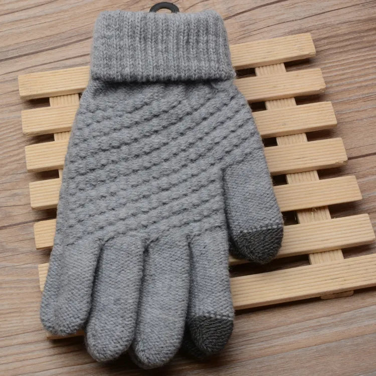 Grauer Strickhandschuh aus Wolle mit Touchscreen-Funktion auf Holzuntergrund.