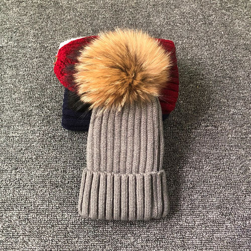 Graue Strickmütze mit Kunstfellbommel, Wintermode, warme Accessoires, modische Kopfbedeckung.
