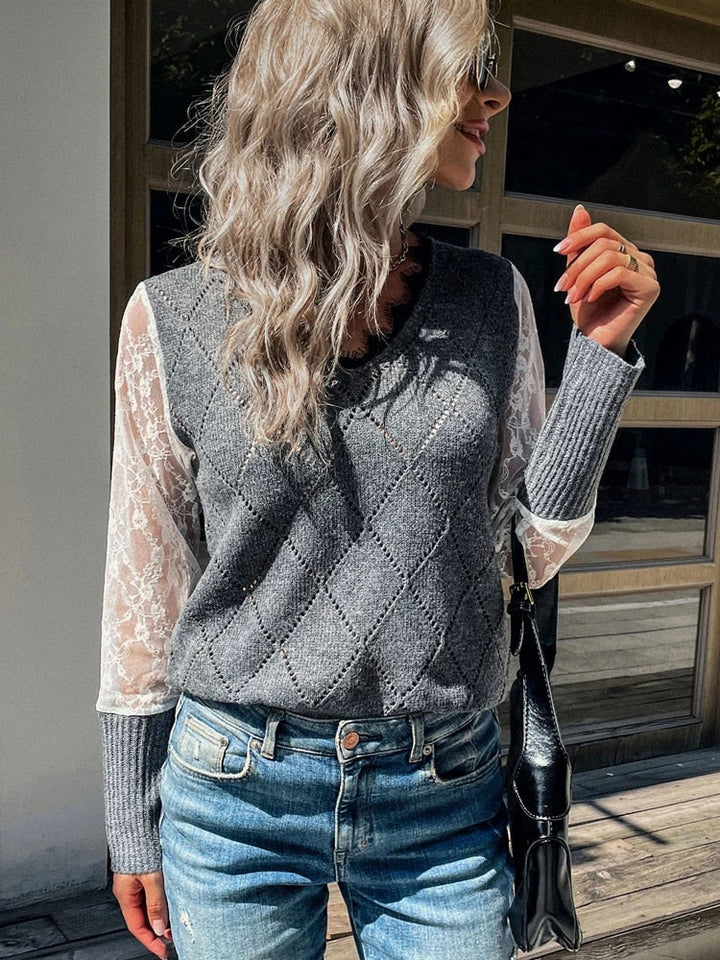 Frau in grauem V-Ausschnitt-Pullover mit Spitzenärmeln und blauer Jeans, modisch, draußen.