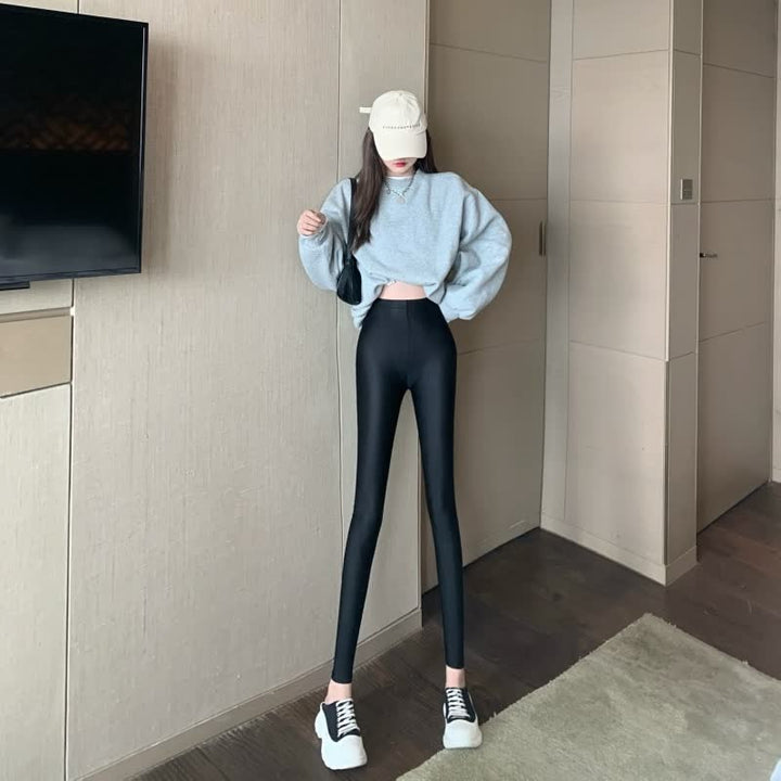 Frau in grauem Pullover und schwarzen Leggings, trägt weiße Sneaker und beige Kappe.