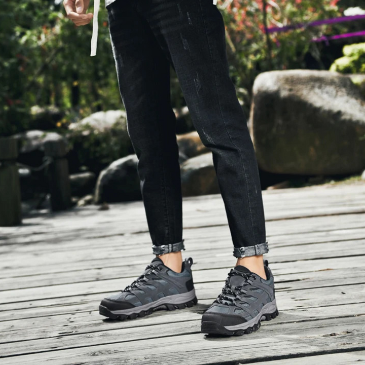 Graue Wanderschuhe, wasserdicht, robust, Outdoor, Herren, auf Holzsteg, Naturhintergrund.