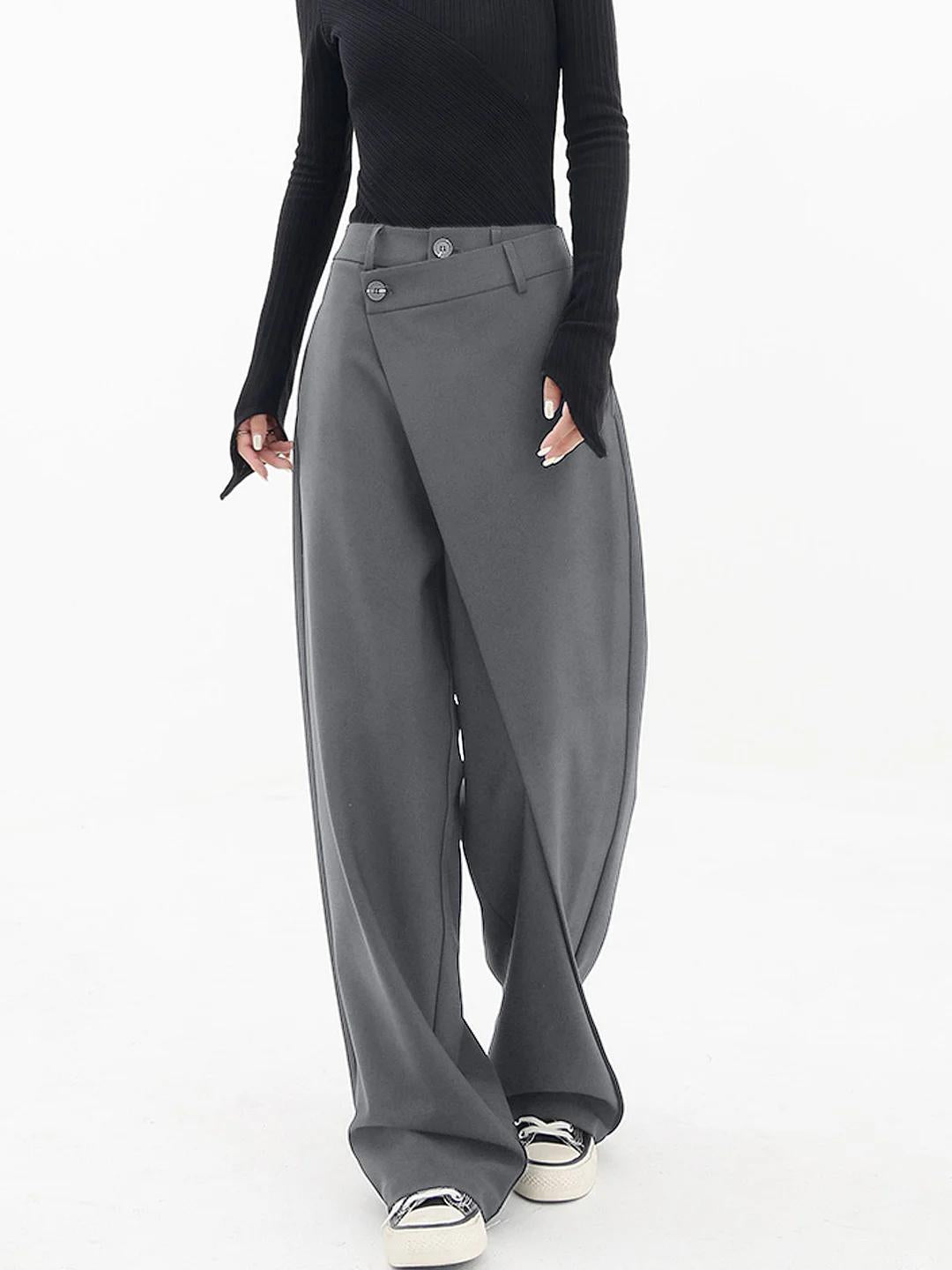 Frau in grauer, weiter Hose und schwarzem Oberteil, modisch, elegant, Streetwear-Look.