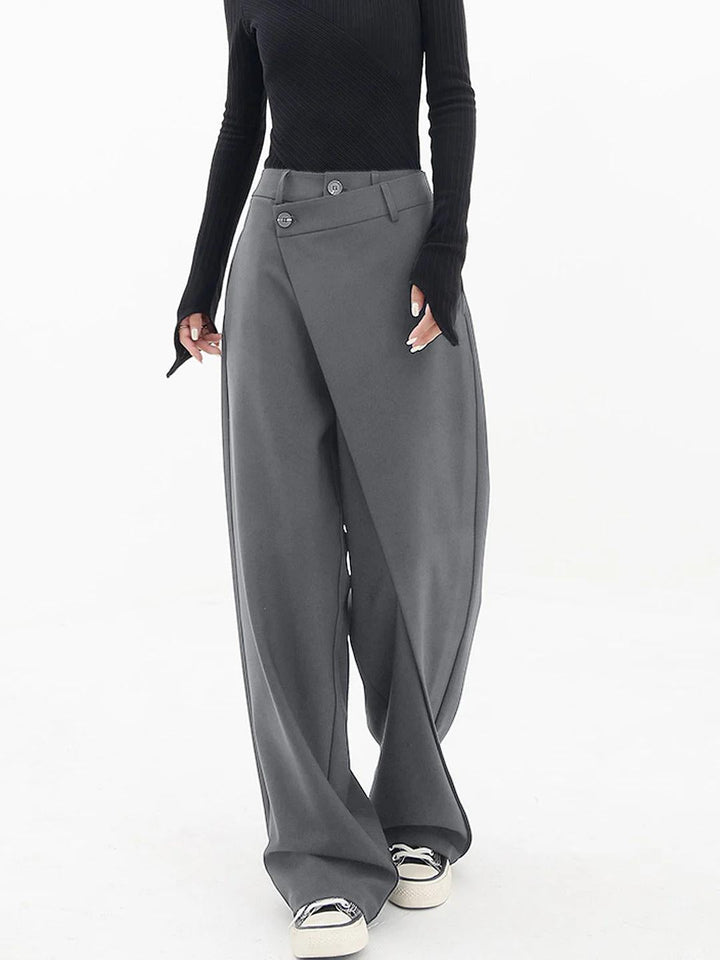 Frau in grauer, weiter Hose und schwarzem Oberteil, modisch, elegant, Streetwear-Look.