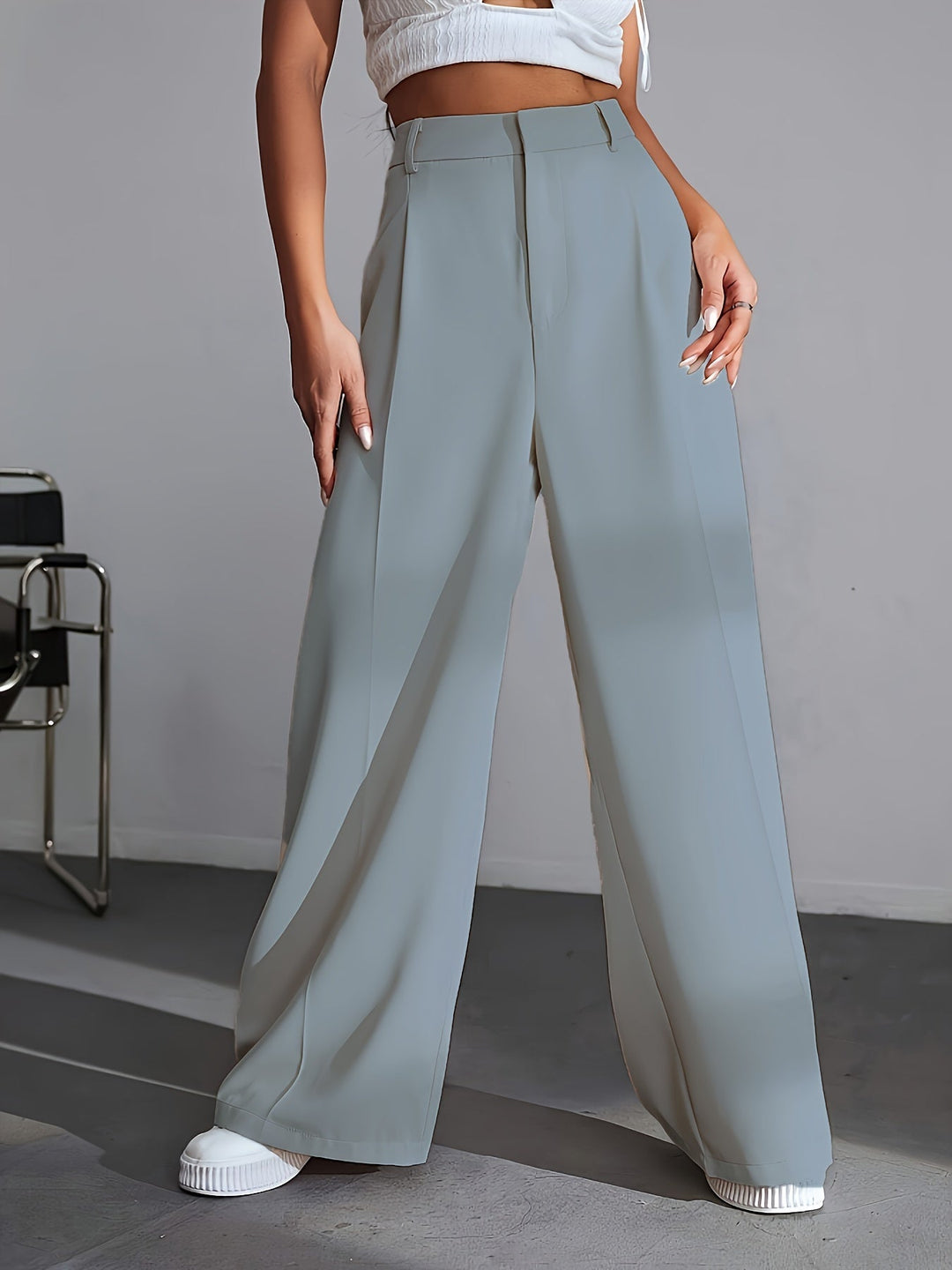 Frau in grauer, weiter Hose und weißem Top, modisch, elegant, Damenbekleidung, Streetwear.