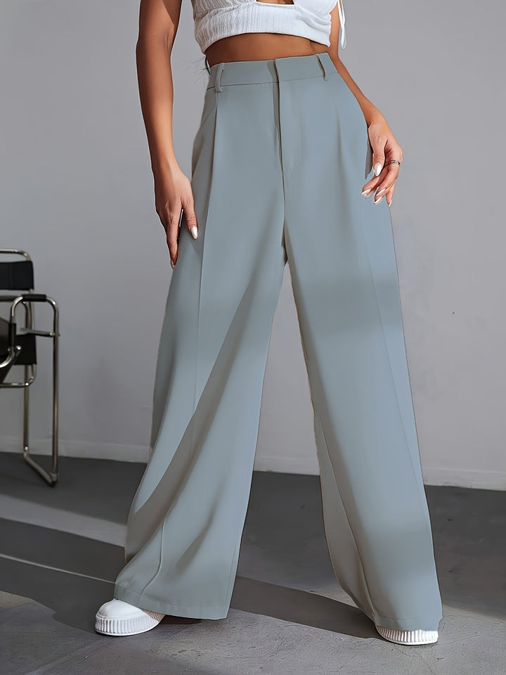 Frau in grauer, weiter Hose und weißem Top, modisch, elegant, Damenbekleidung, Streetwear.