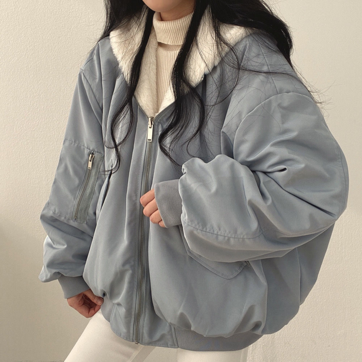 Frau in grauer Oversize-Jacke mit Reißverschluss und weißem Kragen, modisch, Winterkleidung.