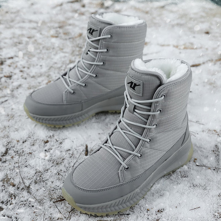 Graue Winterstiefel mit Schnürung, wasserdicht, gefüttert, auf schneebedecktem Boden.