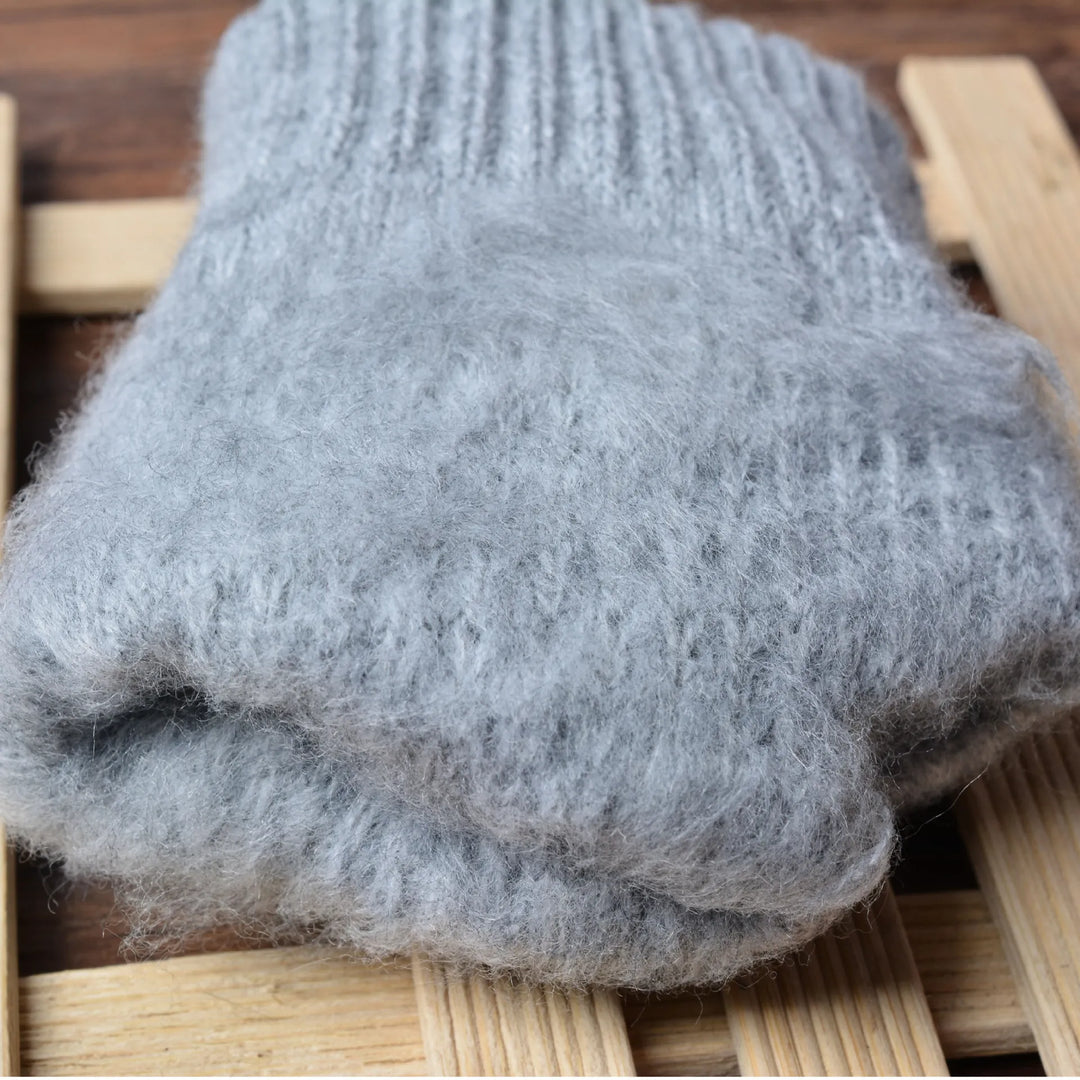 Graue gestrickte Wollsocken, warm und weich, ideal für kalte Wintertage, auf Holzuntergrund.