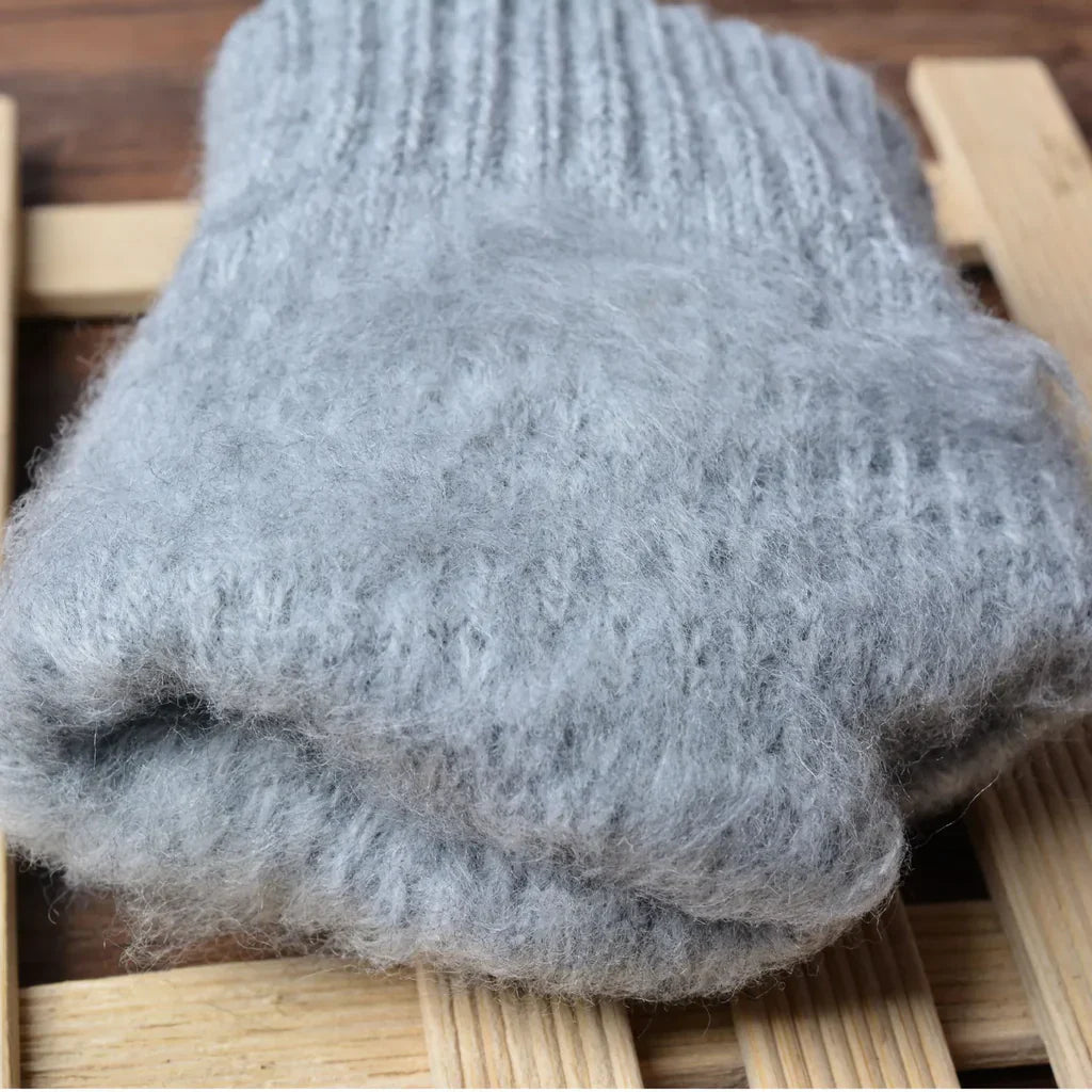 Grauer Wollschal aus Alpaka, weich und warm, auf Holzuntergrund, ideal für kalte Wintertage.