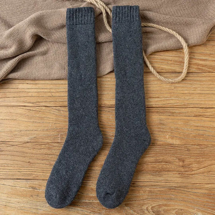Graue Wollkniestrümpfe auf Holzboden, warme Winterstrümpfe, gemütliche Socken.
