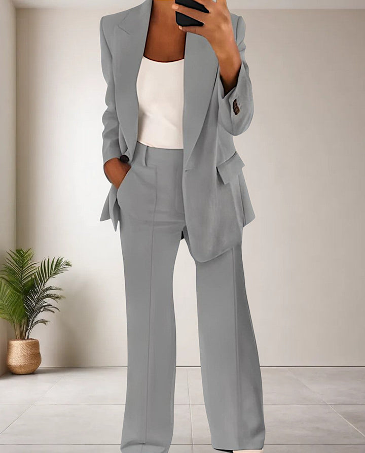 Frau in grauem Hosenanzug, weißes Top, modernes Büro-Outfit, eleganter Business-Look.