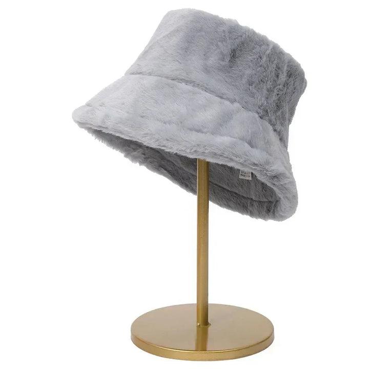 Grauer Kunstpelz-Bucket-Hut auf goldenem Ständer, modisches Accessoire, Wintermode.