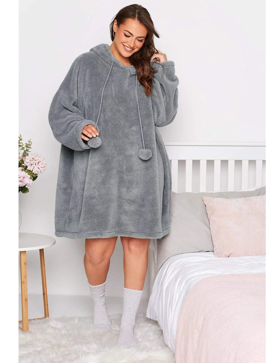 Frau in grauem, übergroßem Fleece-Hoodie-Kleid, gemütlich, modisch, Schlafzimmer.