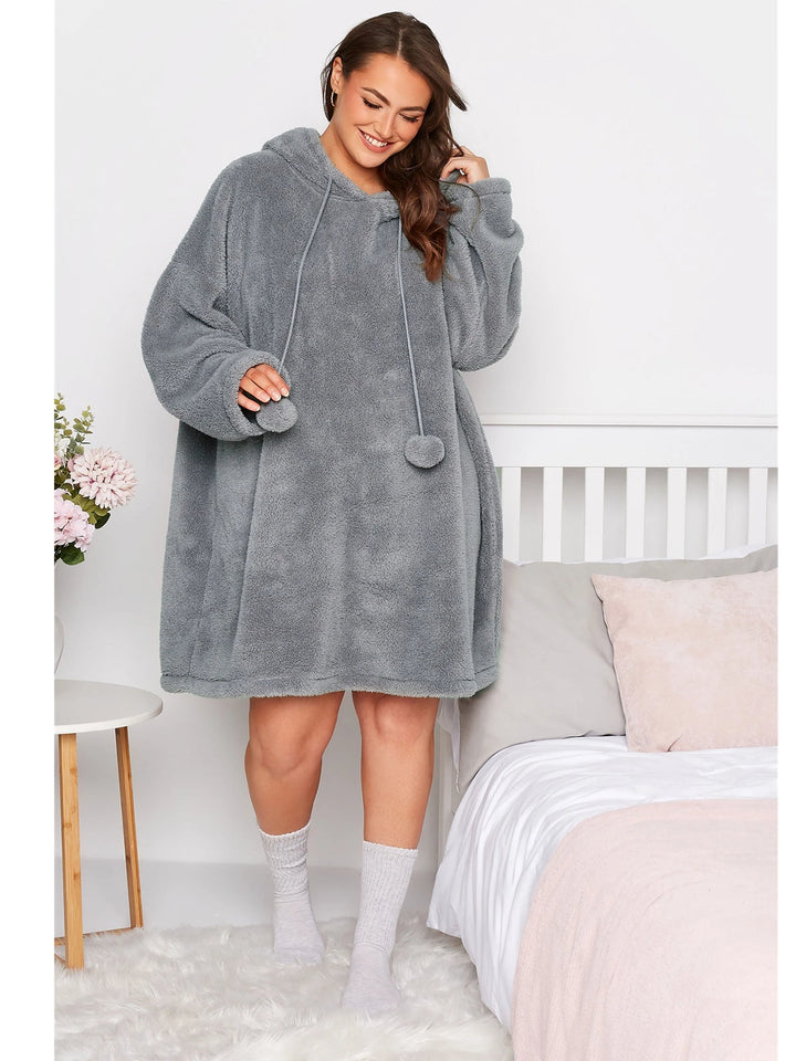 Frau in grauem, übergroßem Fleece-Hoodie-Kleid, gemütlich, modisch, Schlafzimmer.