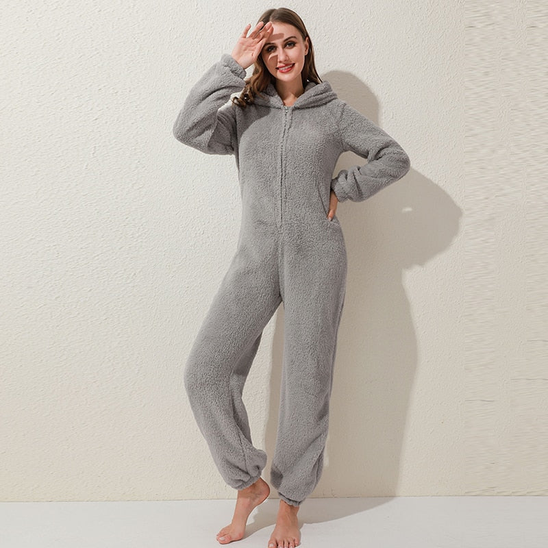 Frau in grauem Fleece-Overall mit Kapuze, gemütlicher Einteiler, Freizeitkleidung.