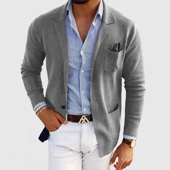 Grauer Herrenblazer mit Reverskragen, Knopftaschen, über blauem Hemd, modisch, elegant.