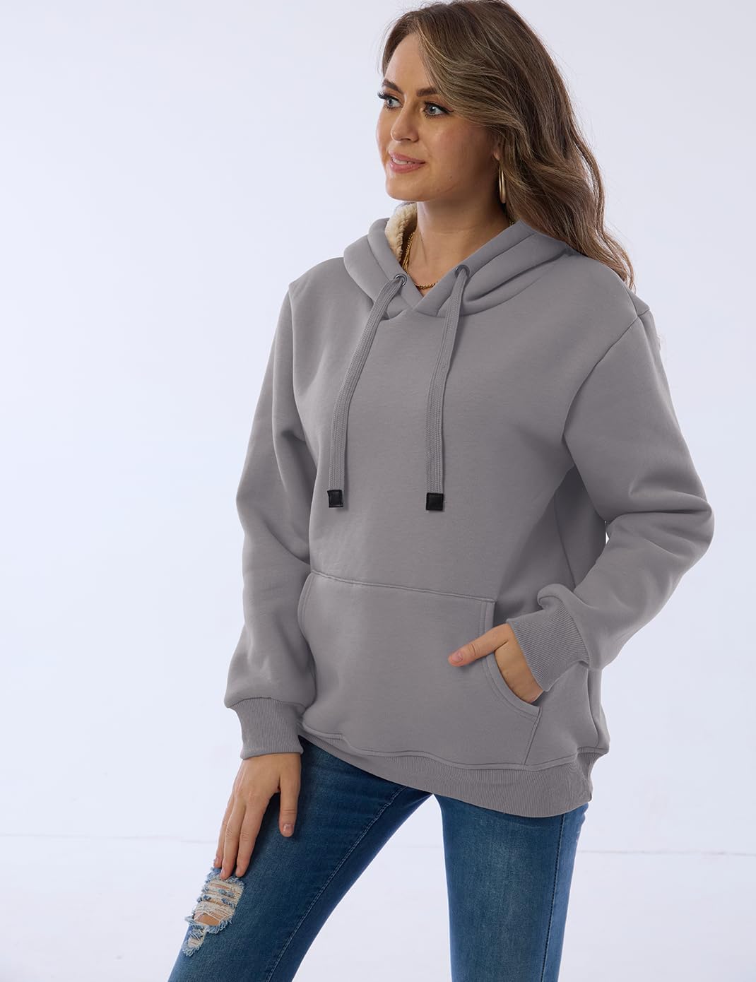 Frau in grauem Kapuzenpullover, Kängurutasche, lässig, bequem, Damenmode, Jeans.