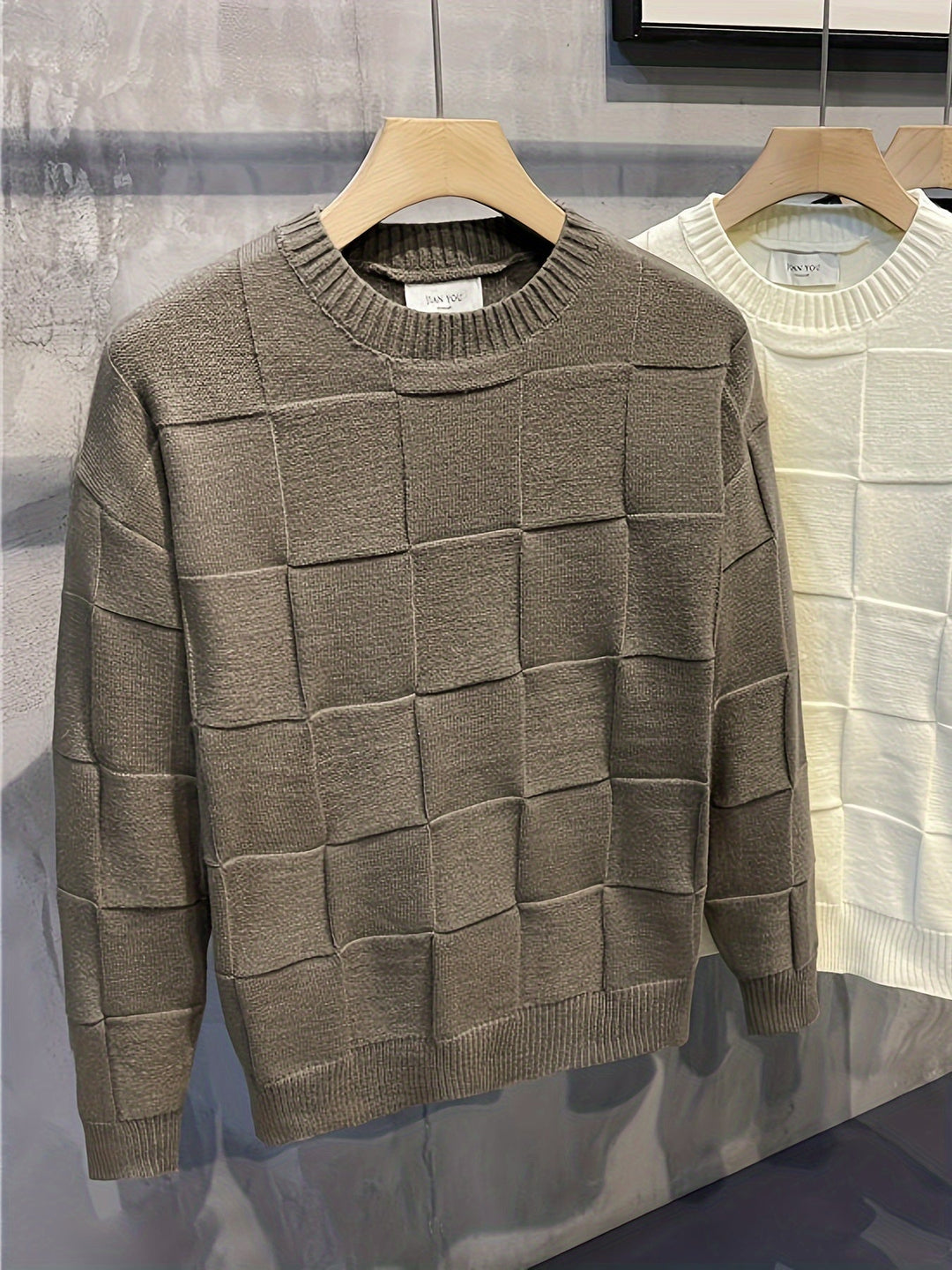 Grauer Strickpullover mit Karomuster, Herrenmode, Baumwolle, Herbst-Winter, auf Holzkleiderbügel.