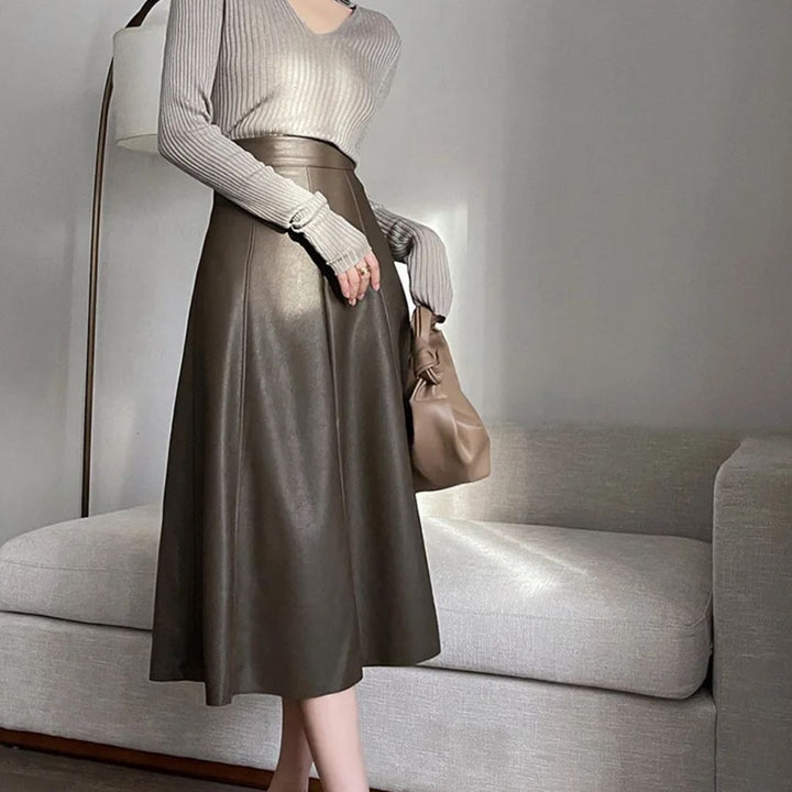 Damenmode: Grauer Pullover, brauner Lederrock, eleganter Look, Wohnzimmer, Herbstmode.