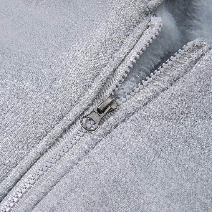 Grauer Reißverschluss auf weichem, flauschigem Stoff, Nahaufnahme, Textil, Modeaccessoire.