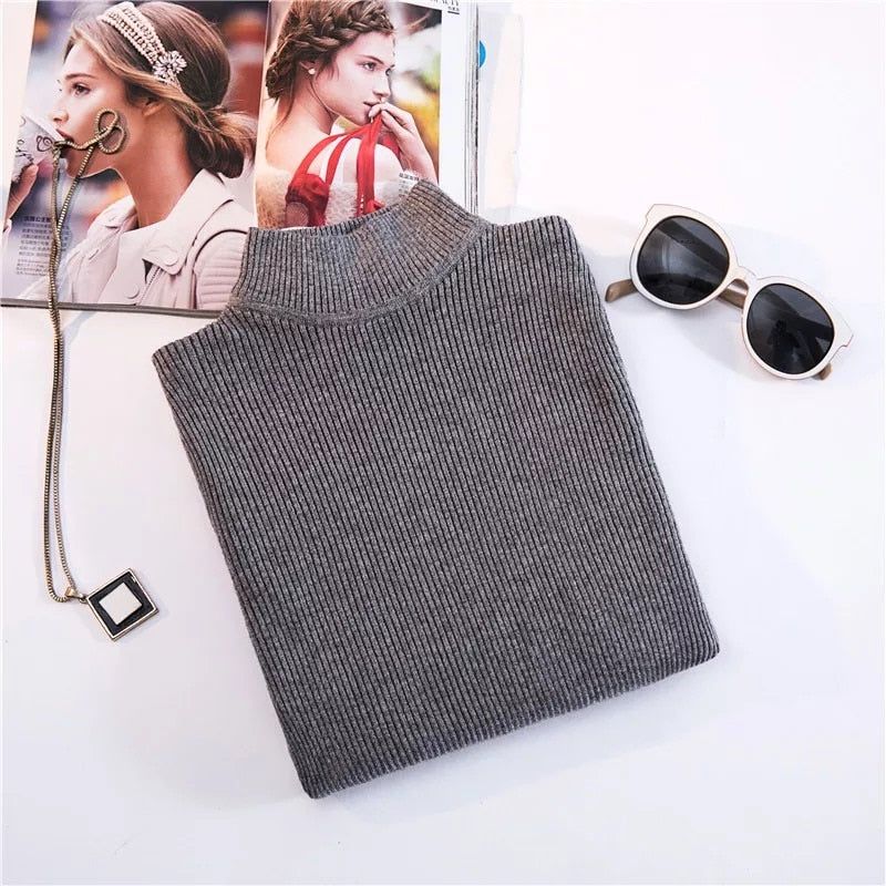 Grauer Rollkragenpullover aus Strick, Damenmode, Herbst-Winter, neben Sonnenbrille und Magazin.