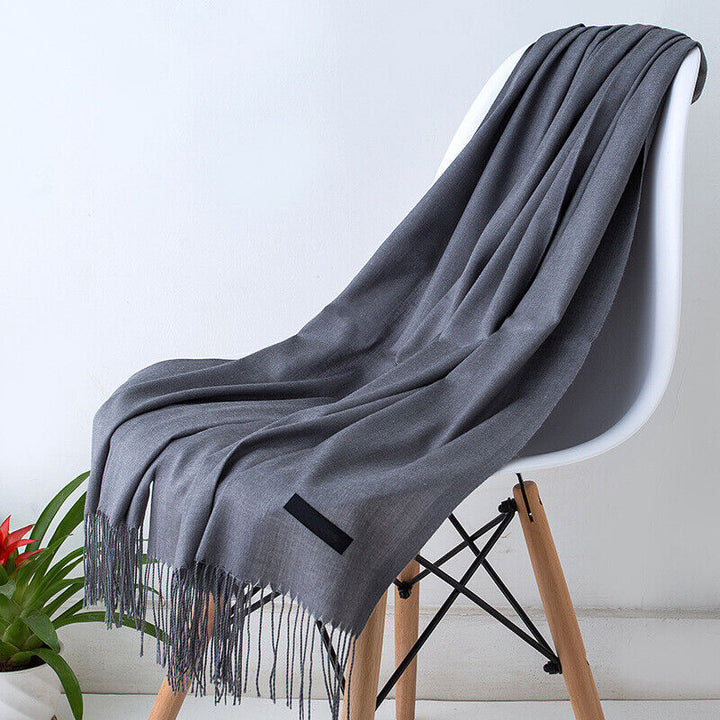 Grauer Kaschmirschal auf weißem Stuhl, weiches Material, modisches Accessoire, Wohnzimmerdekor.