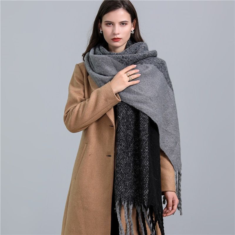 Frau mit grauem Wollschal und beigem Mantel, elegantes Winteroutfit, Modeaccessoire.