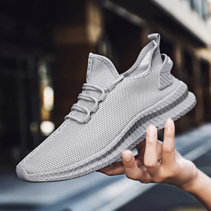 Grauer Herren-Sneaker, atmungsaktives Mesh, sportlich, modisch, Straßenhintergrund.