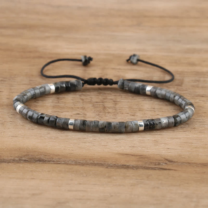 Armband aus grauen und silbernen Perlen, verstellbar, handgefertigt, auf Holzoberfläche.