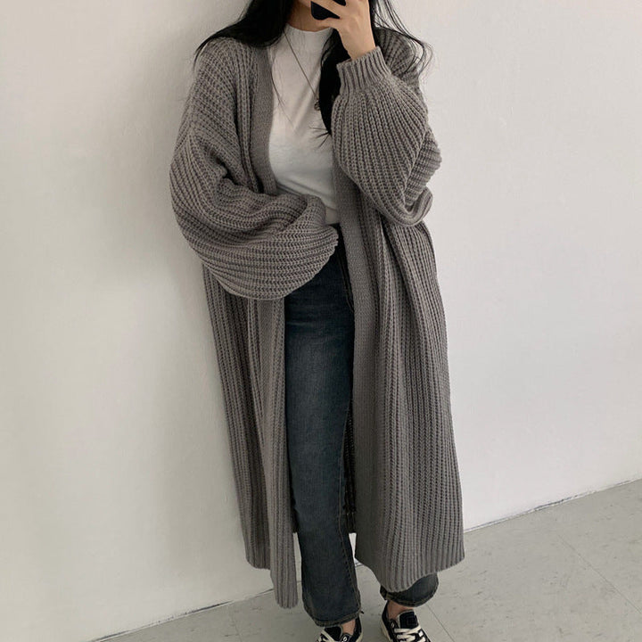Frau trägt grauen, langen Strickmantel, lässiger Stil, modisch, gemütlich, Herbstmode.