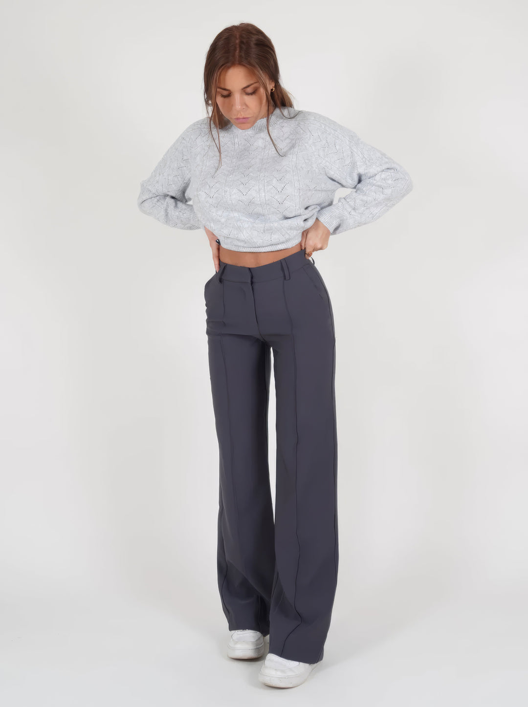 Frau in grauem Strickpullover und dunkelgrauer Hose, modische Damenbekleidung, Wintermode.