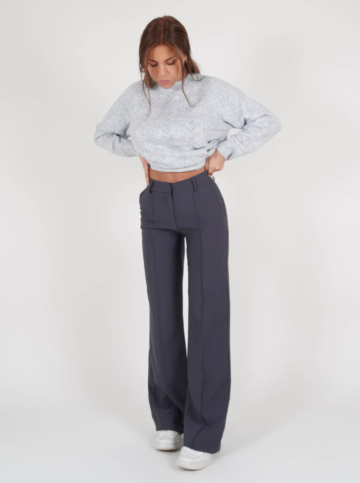 Frau in grauem Strickpullover und dunkelgrauer Hose, modische Damenbekleidung, Wintermode.