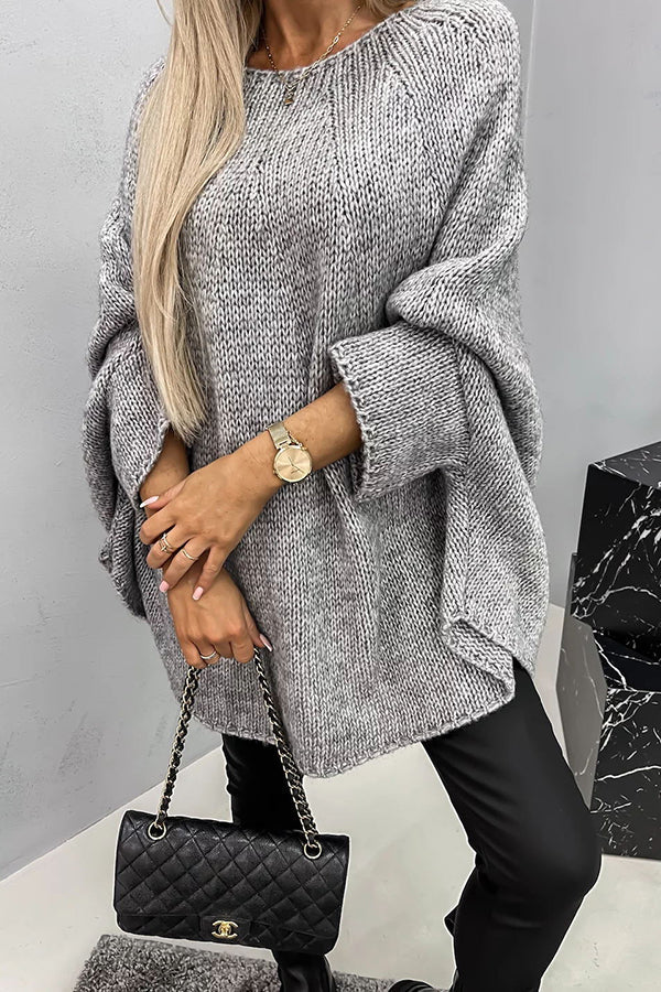 Frau in grauem Strickpullover, schwarze Lederhose, Chanel-Tasche, goldene Uhr.