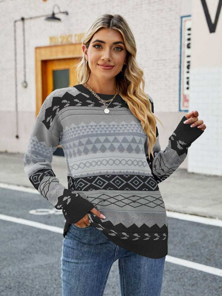 Frau in grauem Strickpullover mit geometrischem Muster, lässig auf der Straße stehend.