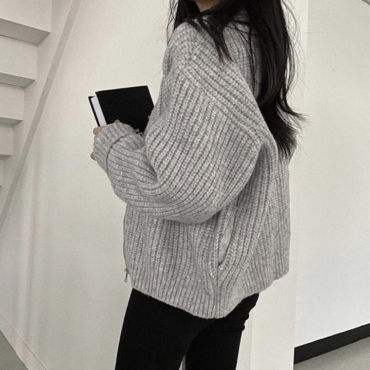 Frau in grauem Strickpullover hält Notizbuch, moderne Mode, gemütlicher Herbst-Look.