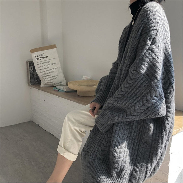 Frau in grauem Strickpullover, gemütlich, modisch, Herbstmode, Innenraum, Tageslicht.